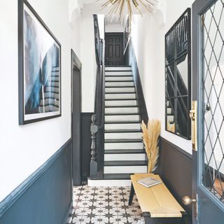 A hallway with star-patterned tiles and a black and white painted staircase