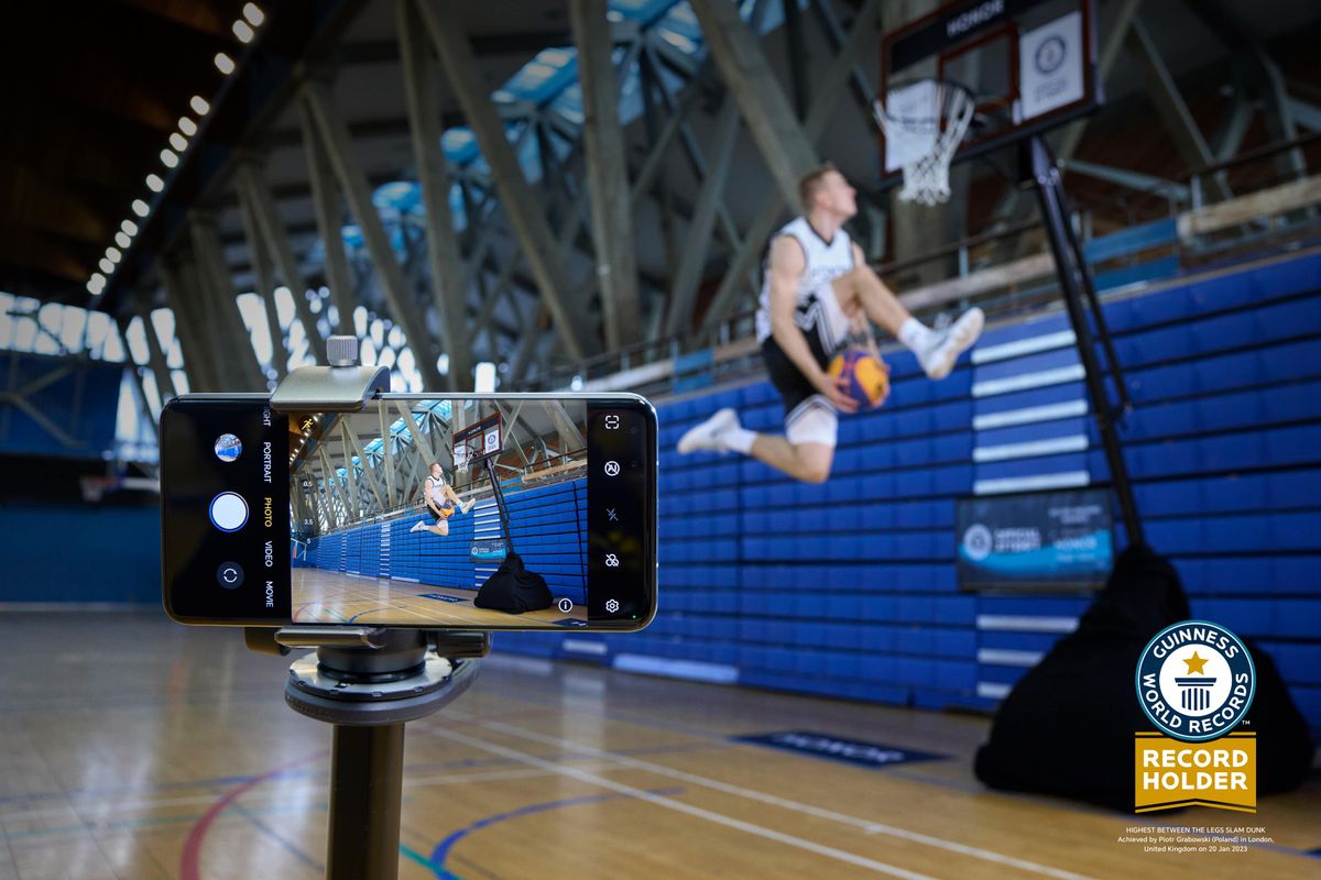 A basketball player mid-air, about to make a dunk, filmed by an HONOR Magic5 Pro smartphone