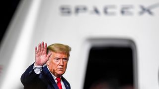 donald trump holding up his hand in front of a spacecraft that has the word spacex on it