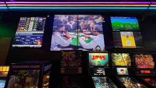 The interior of Pixel Palace arcade and bar showing video games and a bar under bright neon pink lighting. 