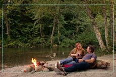 Alexandra Breckenridge as Mel Monroe, Martin Henderson as Jack Sheridan sat by a stream and a campfire in Virgin River