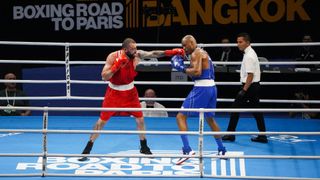 Two men box each other in a ring as a referee walks nearby