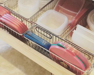 A drawer with wire basket inserts containing tupperware lids and containers