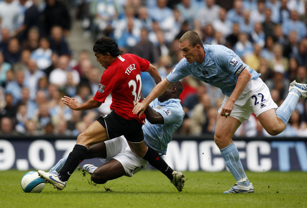 Manchester United's Carlos Tevez (L) breaks past a challenge from Manchester City's Micah Richards (back) and Manchester City's Richard Dunne (R) during the Premiership football match at the City of Manchester Stadium 19 August 2007.