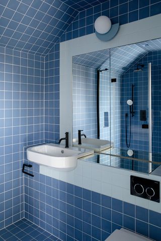 a blue bathroom using the same blue tile on the floor, ceilings, and walls