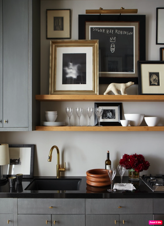 A modern gray kitchen with open shelving above a sink