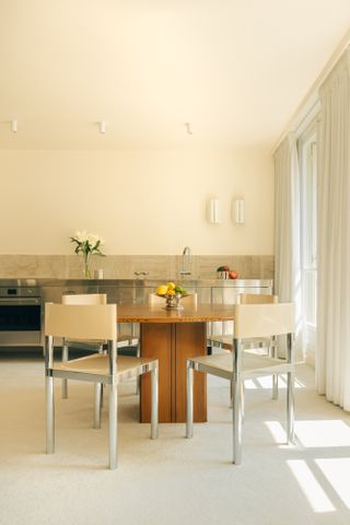 Kitchen with pale magnolia walls, steel units and wood table with steel chairs