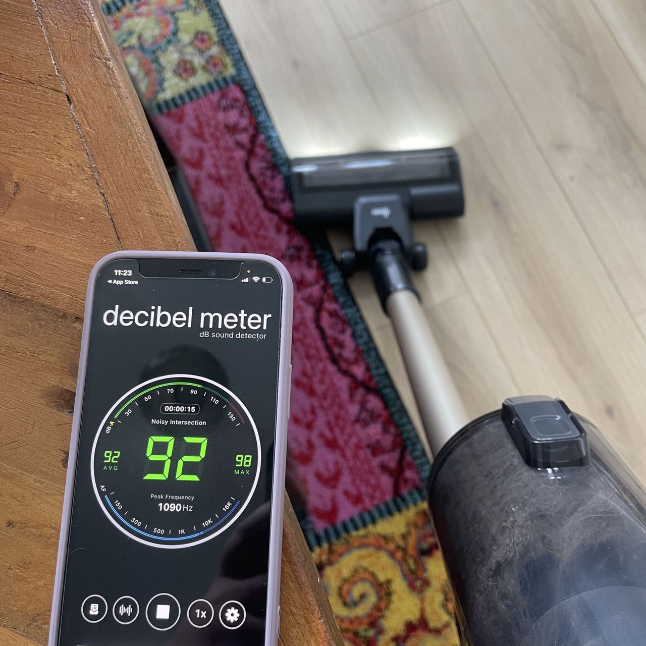 Hoover HF3 vacuum next to a phone on a table, showing a decibel meter app with a reading of 92dB