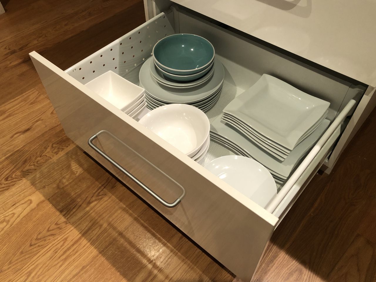 Open kitchen drawer with stacks green and white plates Getty Images - DLMcK