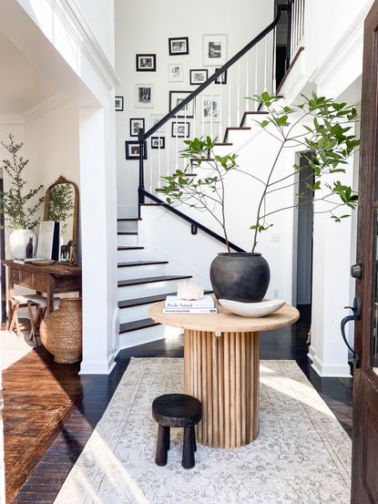 Modern entryway with gallery wall running up the stairs and small round console table at ground floor level