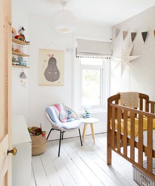 A baby girl nursery idea with a pale gray wall with white painted stars on it, and wooden crib.