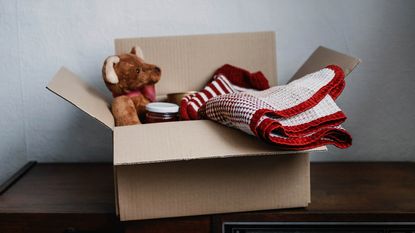 A box with a teddy bear and a blanket.