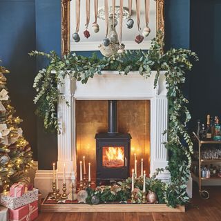 Living room mantlepiece with roaring log burner and decorations