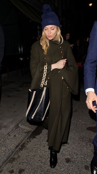 Sienna Miller wearing cosy beanie and khaki trench coat