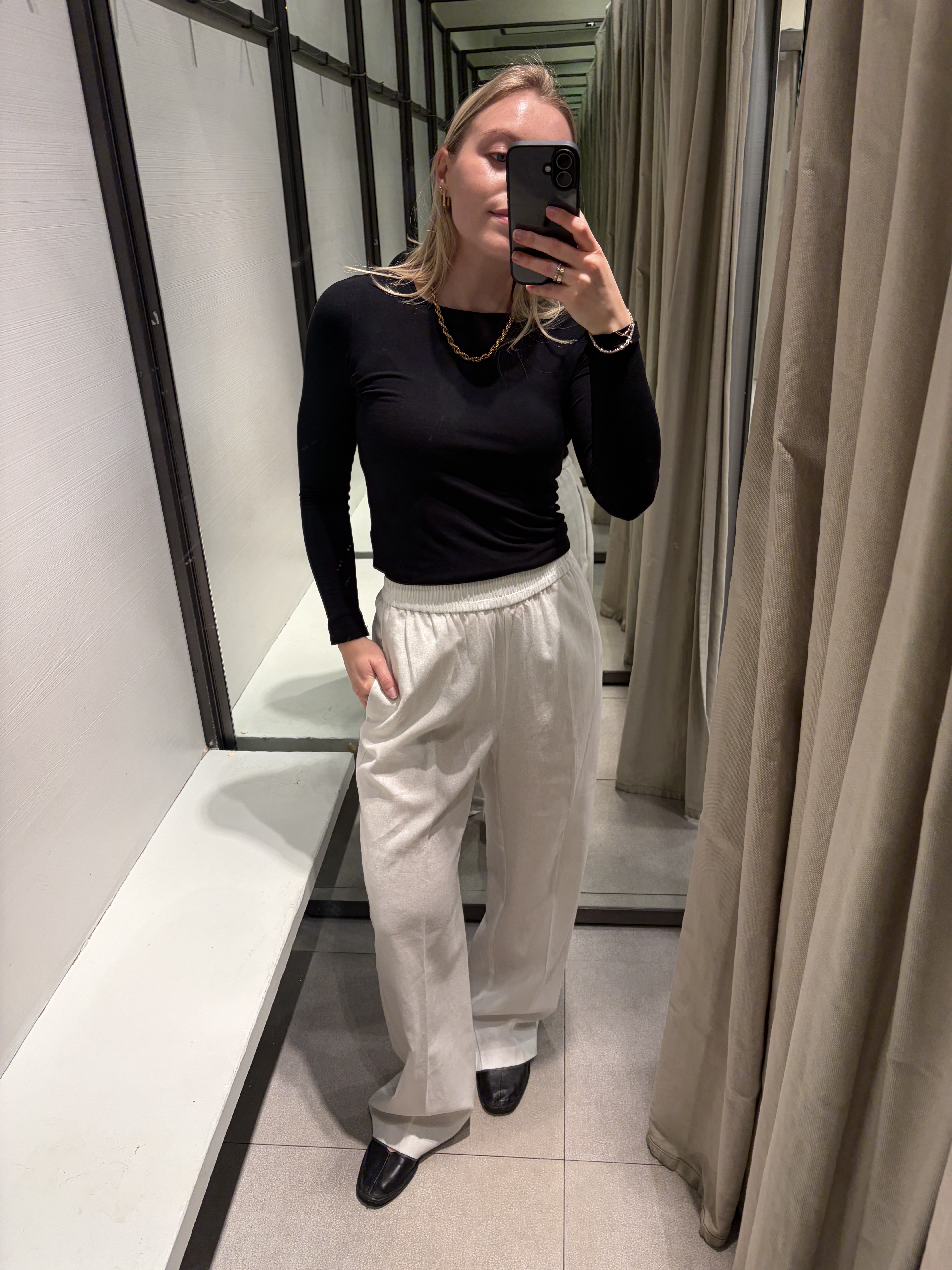 Woman wears black top, white linen trousers