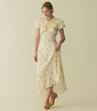 seorang model mengenakan gaun midi lengan pendek bermotif bunga kuning