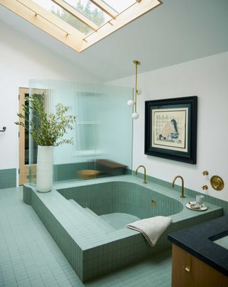 a deep sunken tiled bath with green tiles