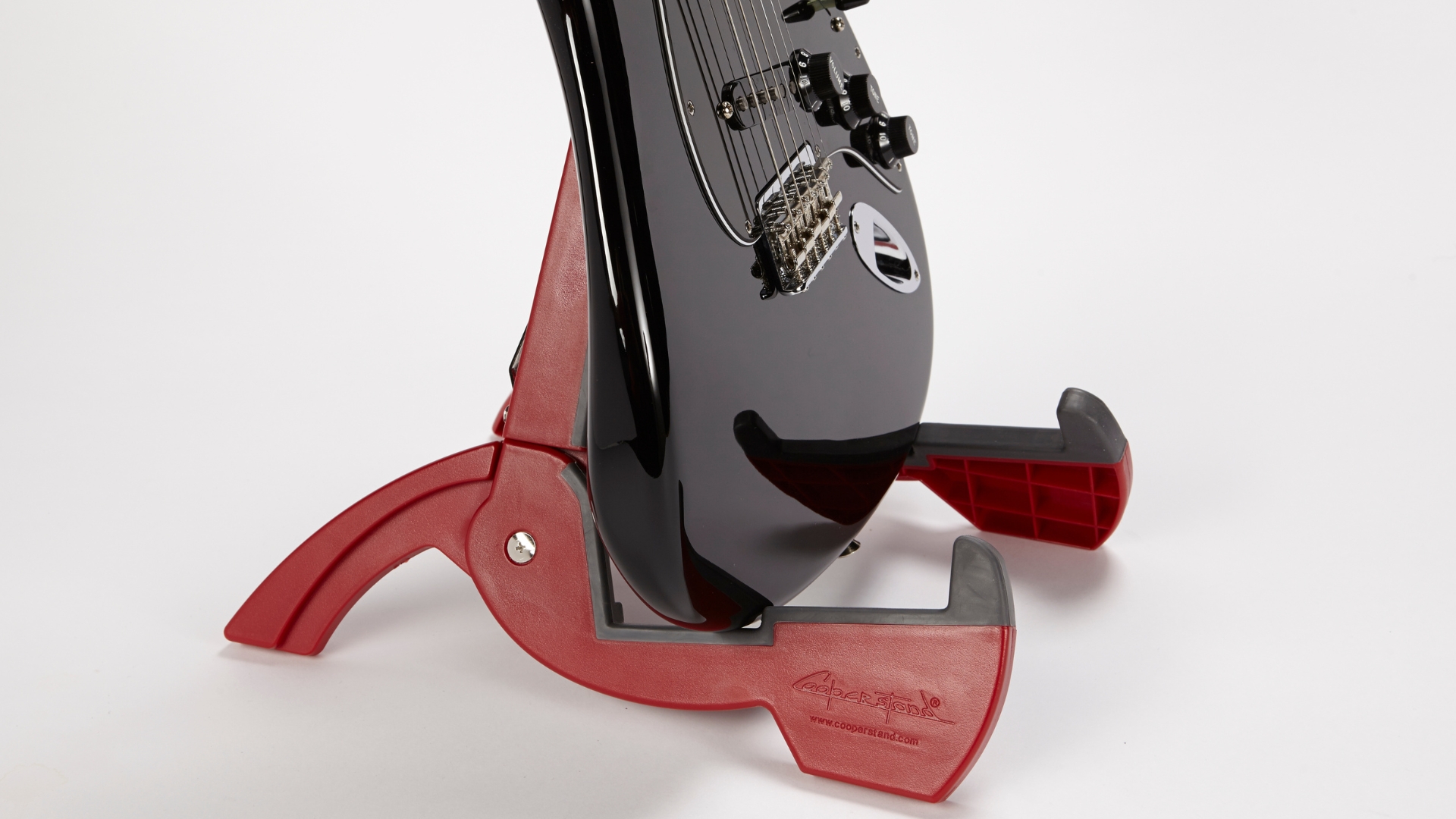 An electric guitar on a red guitar stand
