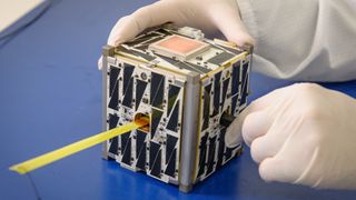 Close-up image of a cubesat being handled by an engineer