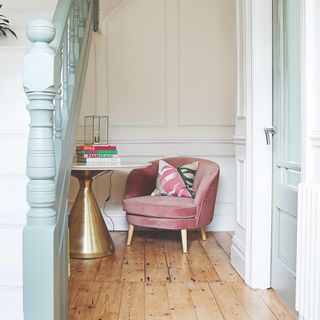A reading corner under the stairs with pink velvet chair