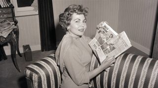 Simone Silva holds newspapers showing her topless photo session in Cannes in 1954