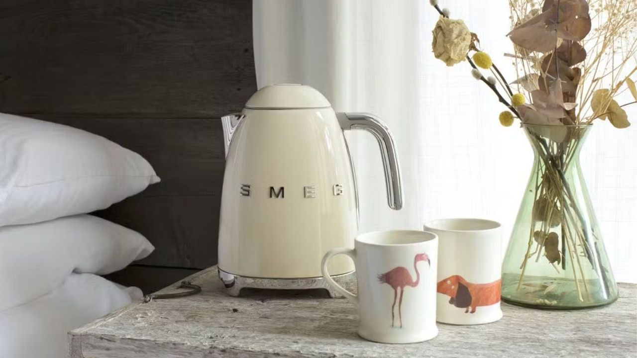 A Smeg 50s Retro Kettle with two cups on a bedside table