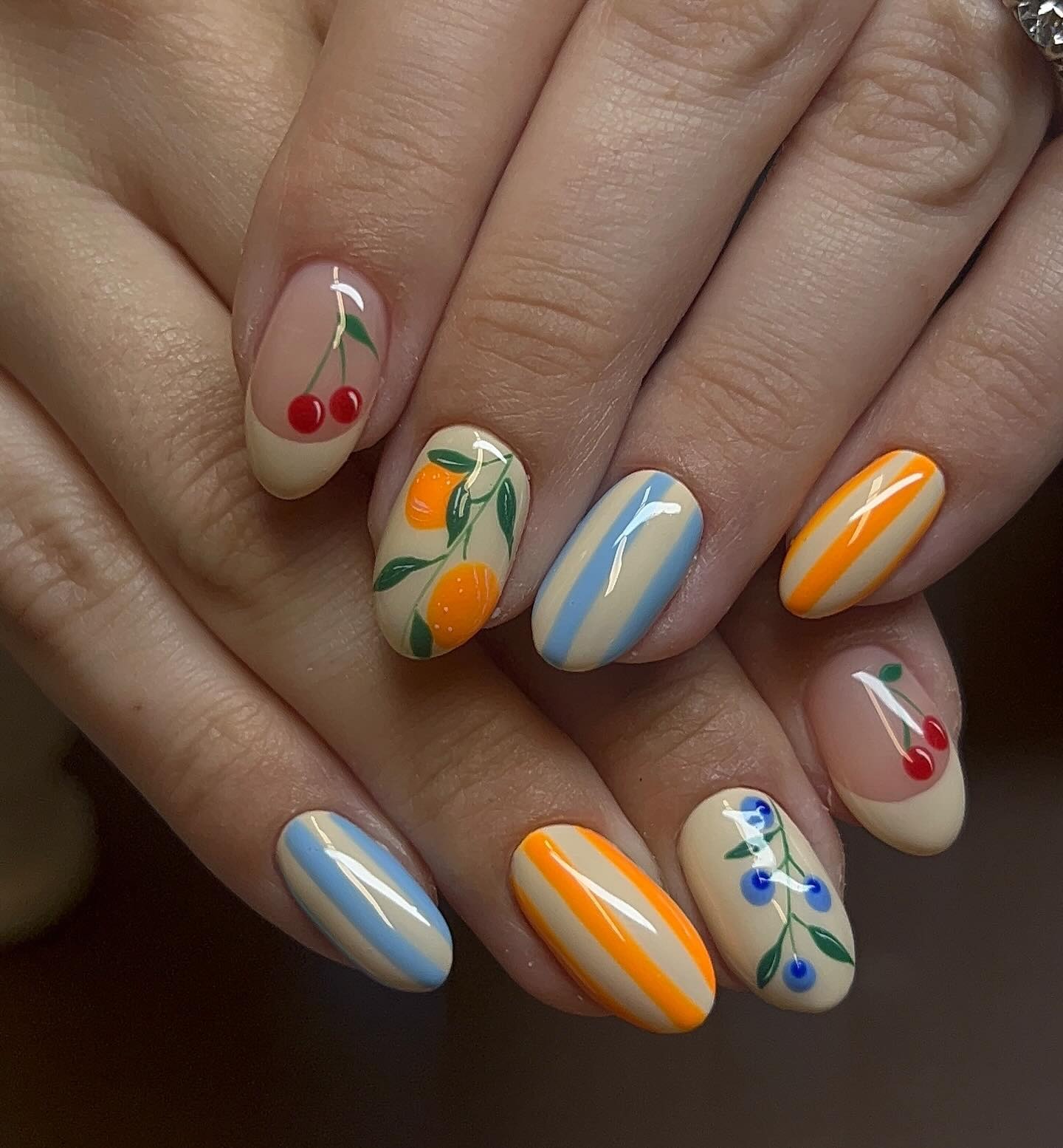 Mismatched nails with French tips, fruits, and nautical stripes.