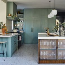 Open plan kitchen with green/blue interior and a large island with stools 