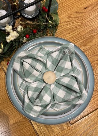 Green gingham napkin folded into a Poinsettia flower