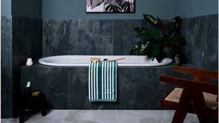 Dark bathroom idea with matching dark green bath panels and splashback and lighter shade of green painted on the walls