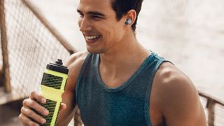 a man taking a break from working out while wearing the cleer roam nc wireless earbuds