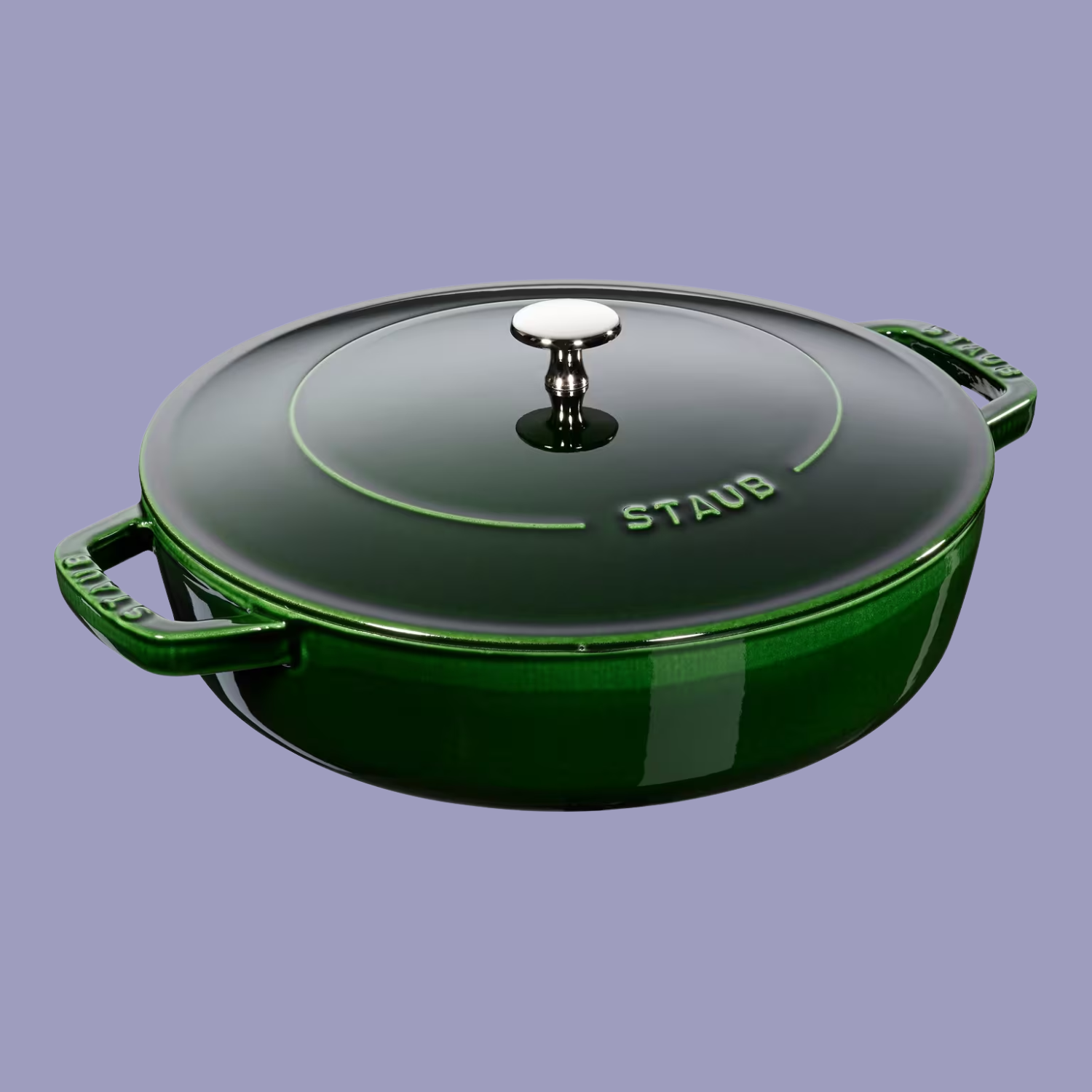 A glossy moss green round cast iron saute pan from STAUB, against a lilac purple background