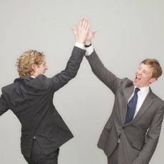 Two men in suits high five.