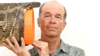 A man measures the mouth of a snake.