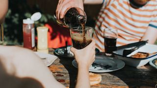 Woman's hand pouring cold into glass