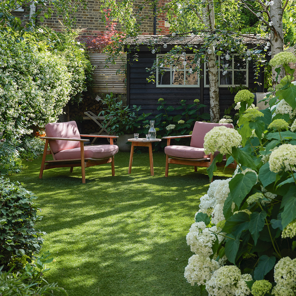 green lawn with green trees and pink chair