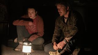 Ellie (Bella Ramsey) and Joel (Pedro Pascal) lit by a camp lantern in The Last Of Us episode 5