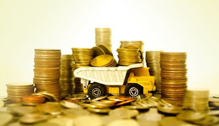 yellow toy dump truck holding and surrounded by piles of gold coins