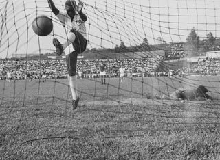 Pele smashes the ball into the net after scoring for Santos against Guarani in 1958.