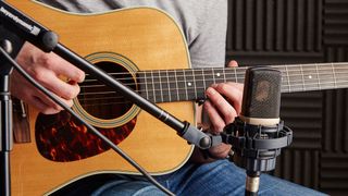 Close-up of a condenser microphone and acoustic guitar