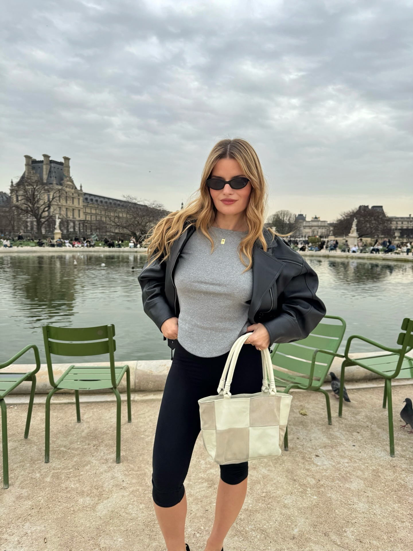 A woman in Paris wearing a black leather jacket with wavy, honey blonde hair