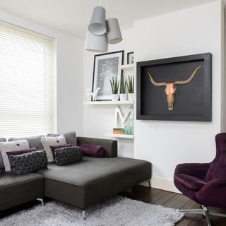 living room with white wall grey sofa with designed cushions frame on wall and window