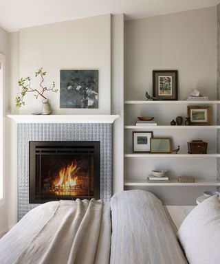 neutral bedroom with shelving, fireplace, neutral bedding