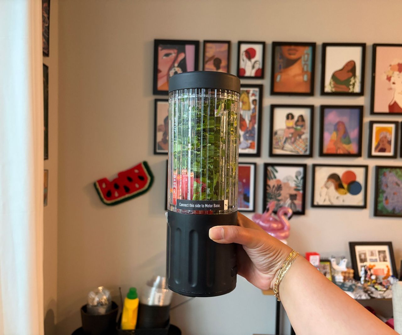 Green leafy sauce ingredients inside a small portable blender with a black base and lid.