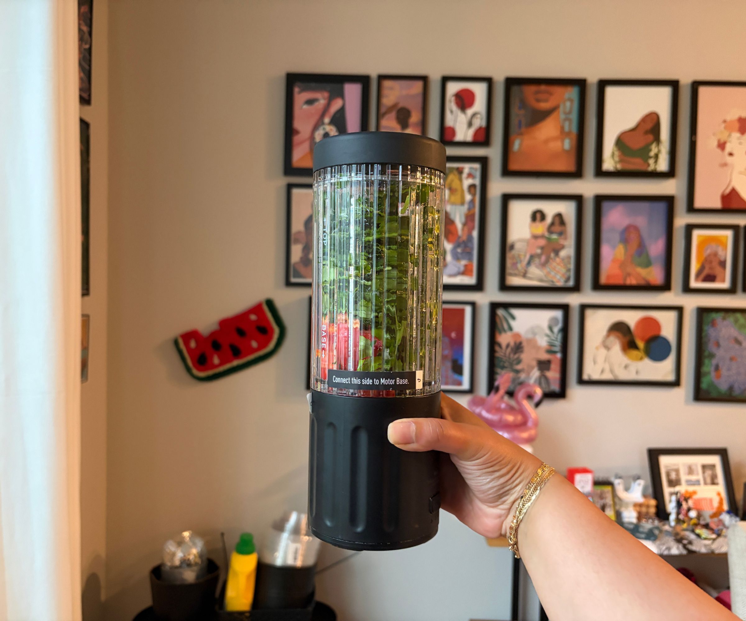 Green leafy sauce ingredients inside a small portable blender with a black base and lid.