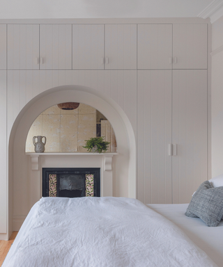 inbuilt cupboard surrounding fireplace in white bedroom
