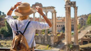 Woman looking across the Roman Forum in Rome wearing sunhat