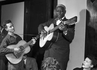 Woody Guthrie (left) and Lead Belly perform together in Chicago, Illinois, circa 1940