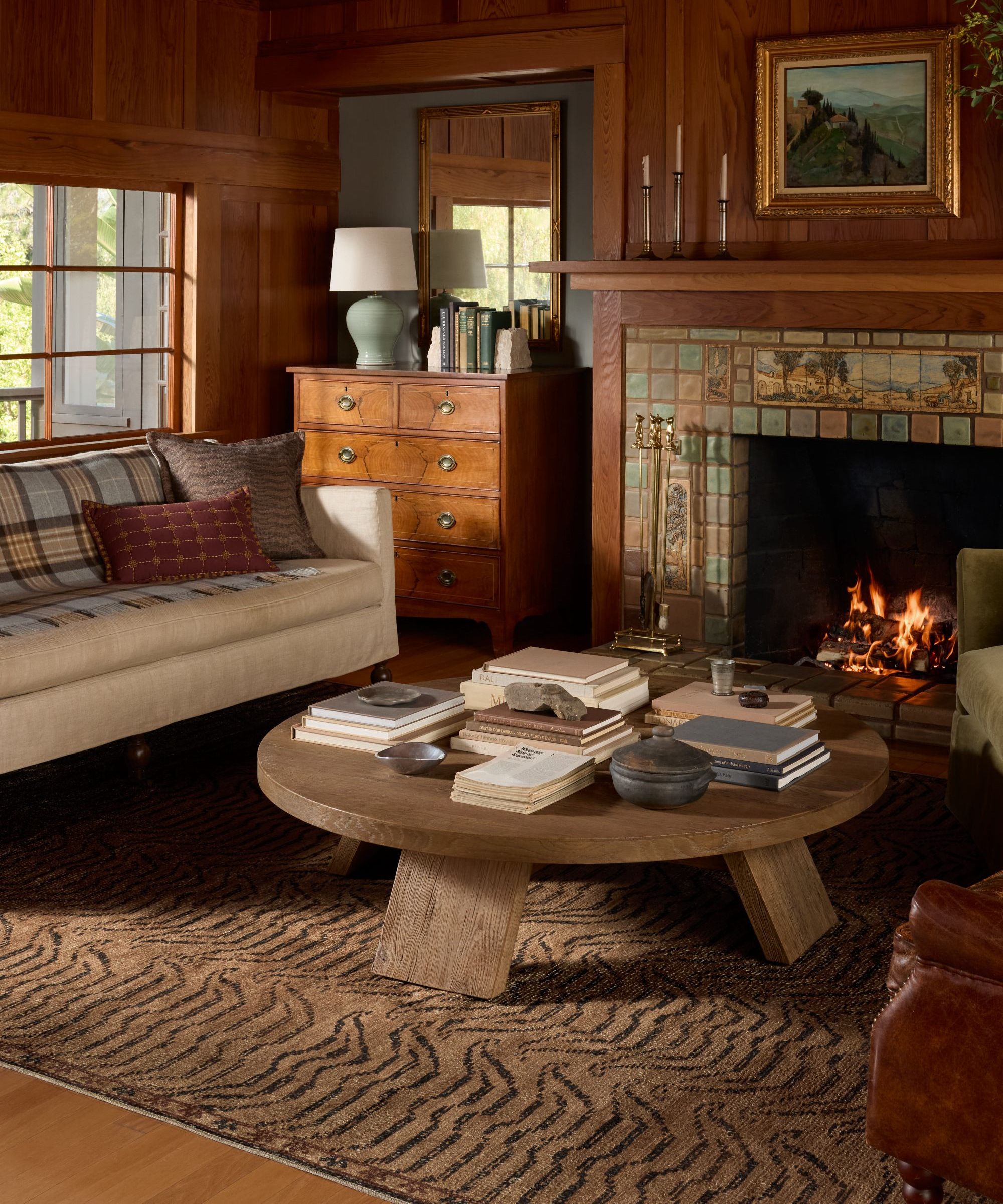 a cozy living room with a printed rug, a large coffee table, and a large fireplace
