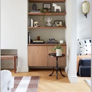 White living room with wooden parquet flooring and styled bookcase shelving
